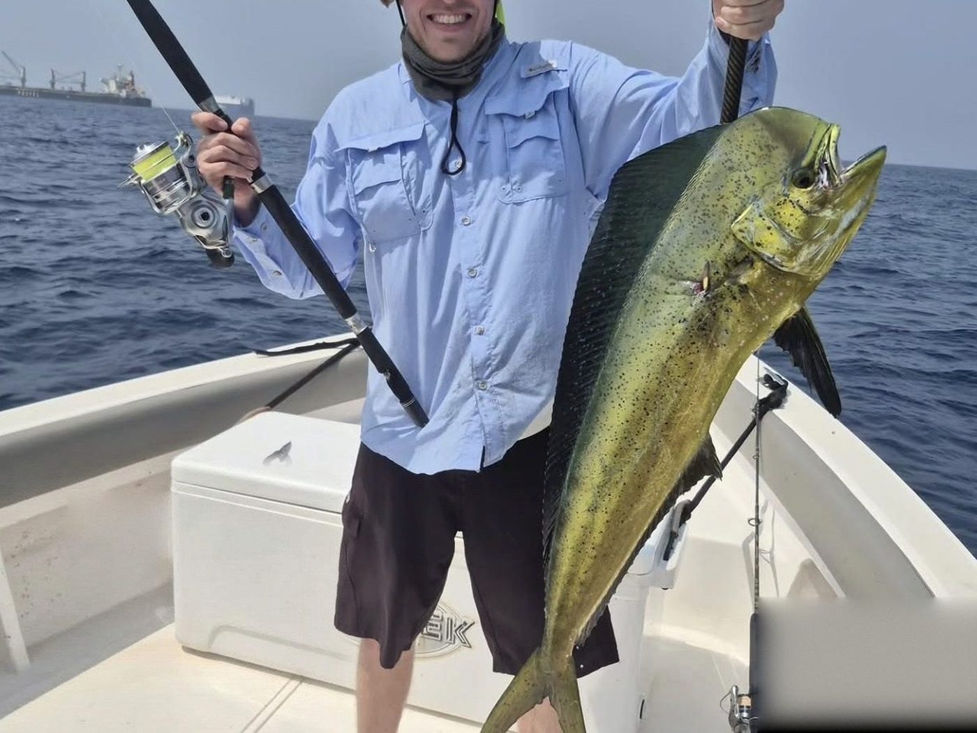 An angler holding his rod and a dorado on the deck of a charter boat in Fujairah