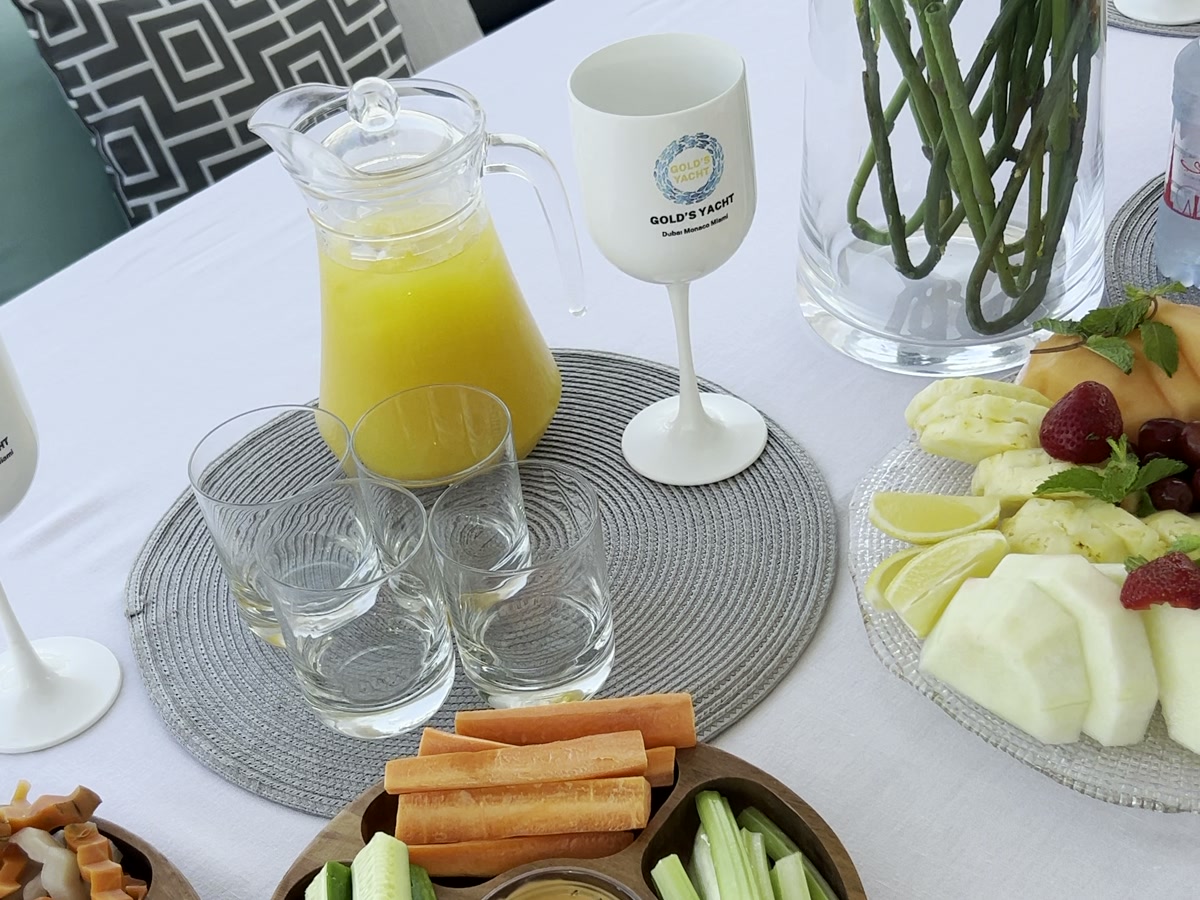 Jug of fresh juice and Gold's Yacht branded glasses on a set table aboard a yacht in Dubai